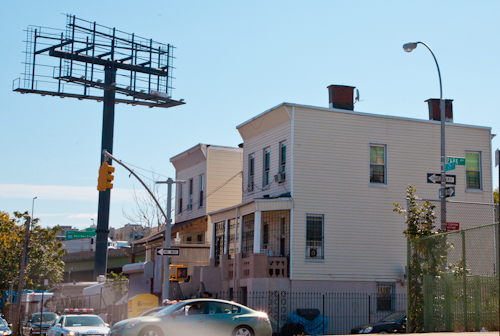 Houses and billboard frame abut the Cross-Bronx Expressway at 175th St. and Park Ave., Bathgate neighborhood, Bronx, NY. Photo by Pat Arnow