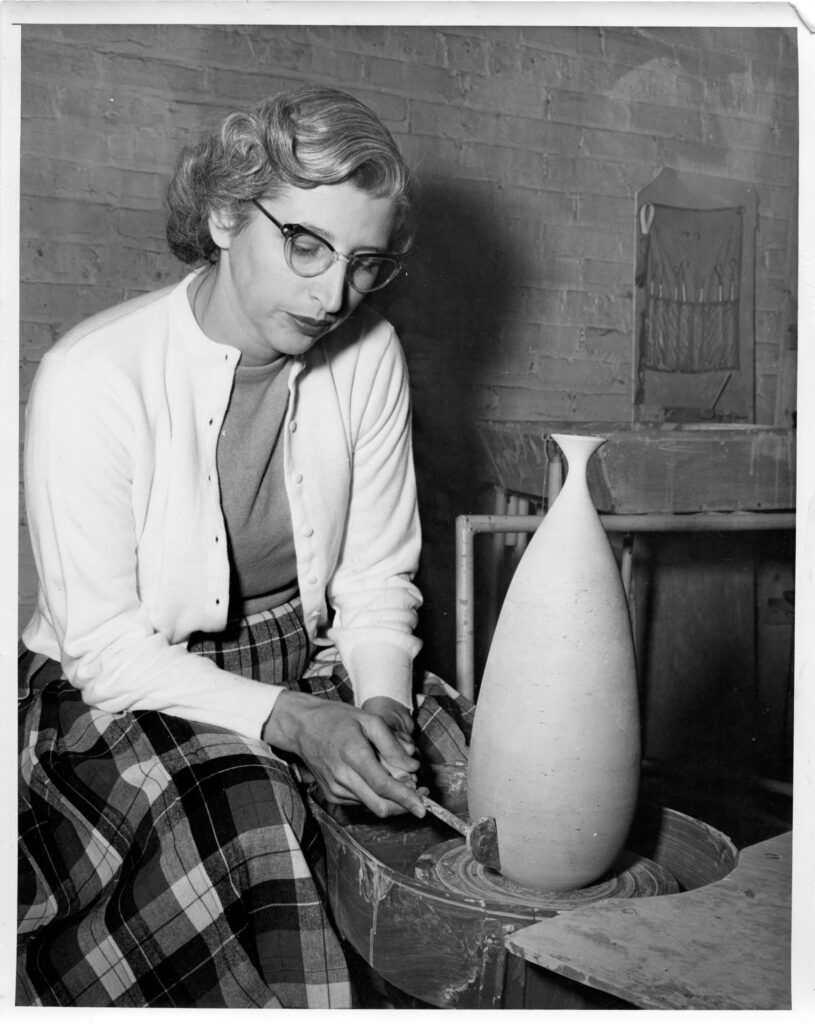 Edna Arnow footing a pot, all dressed up for a photo for a newspaper article about her. About 1961. 