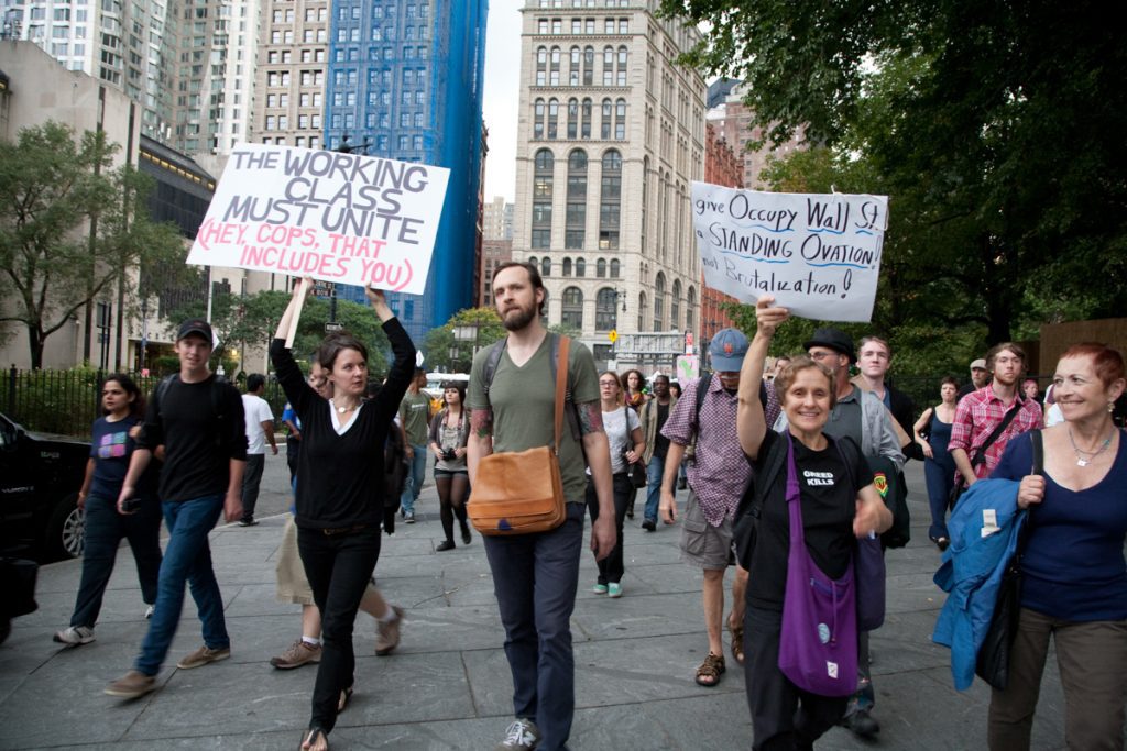 Occupy Wall Street marchers with signs, "The working class must unite (hey cops, that includes you)