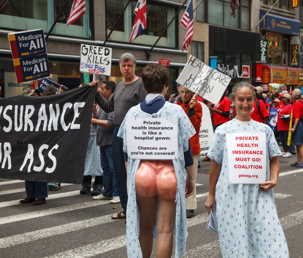 Labor Day Parade, 2009, marchers wearing hospital gown, open in back with plastic butt showing and sign: "Private health insurance is like a hospital gown. Chances are you're not covered."